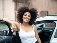 Jovem mulher sorri segurando chaves do carro